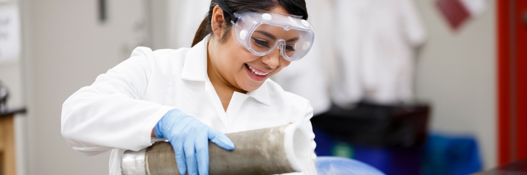 A student smiles while performing a lab experiment.