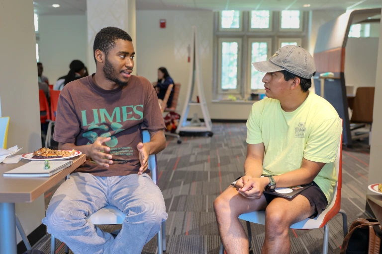 Two students discuss their research over pizza