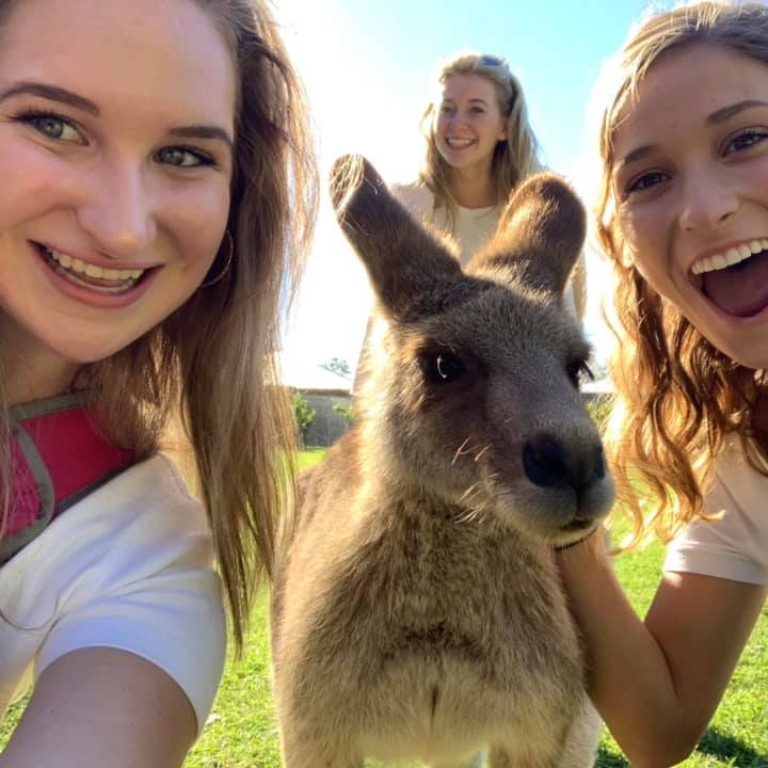 Autumn Brown and a friend pose with a small kangaroo while studying in Australia with HIEP in 2019