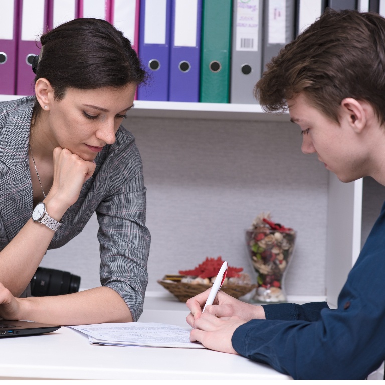 Student and advisor sitting and speaking at a desk.