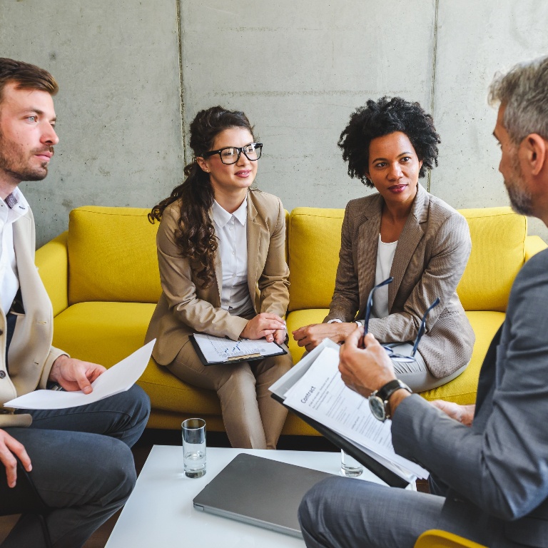 A formal meeting between four people sitting on a couch.