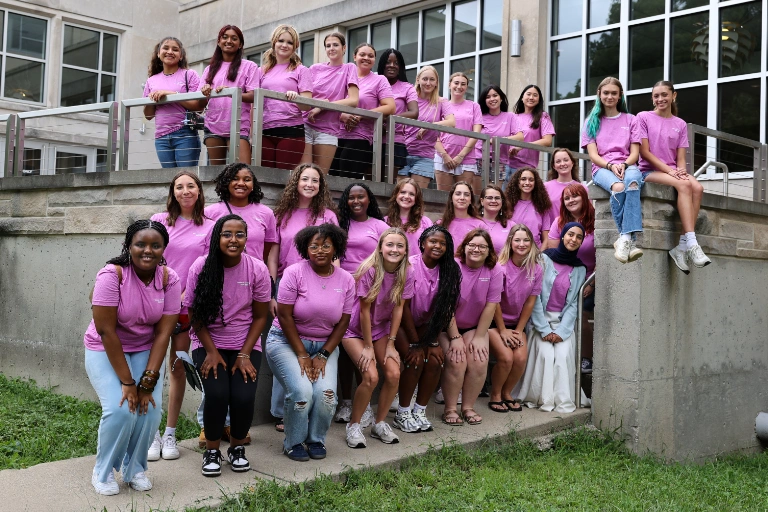 A group of students pose together in purple shirts